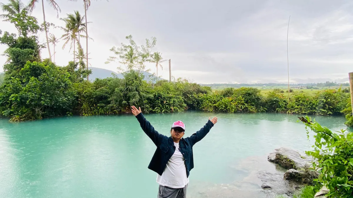 pengunjung berfoto di tepi danau ranolewo dengan latar pegunungan