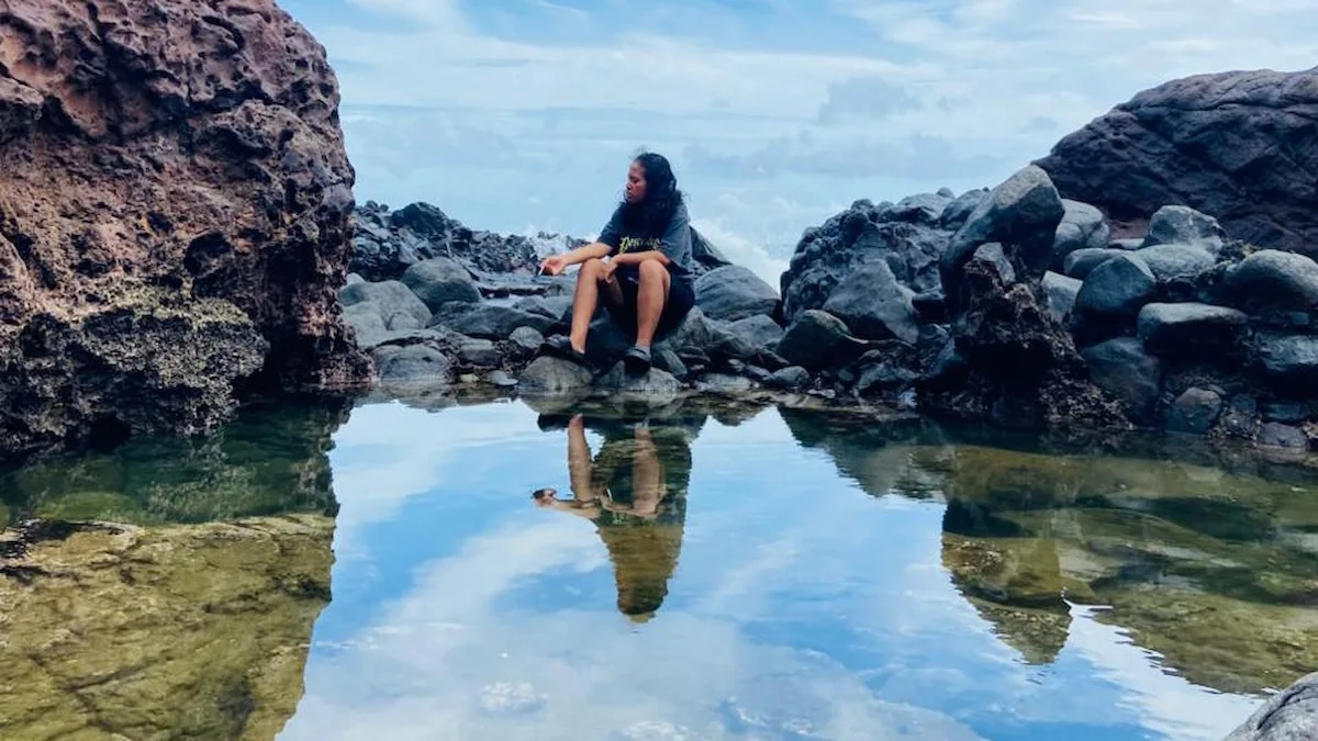 pengunjung menikmati kolam alami di sela batu karang