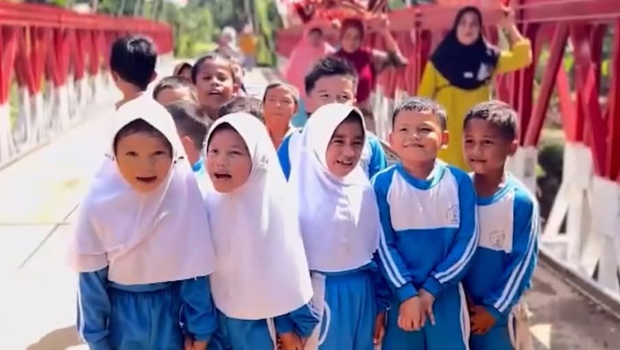 anak sekolah dasar melintasi jembatan merah menuju sekolah bersama teman