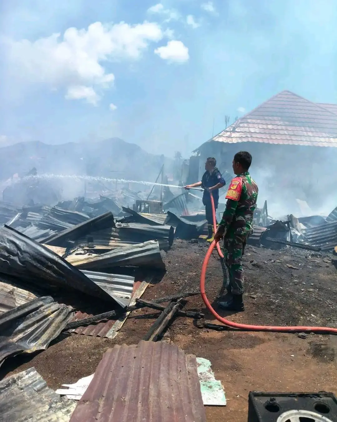 petugas dan tni padamkan api kebakaran singkil manado di lokasi