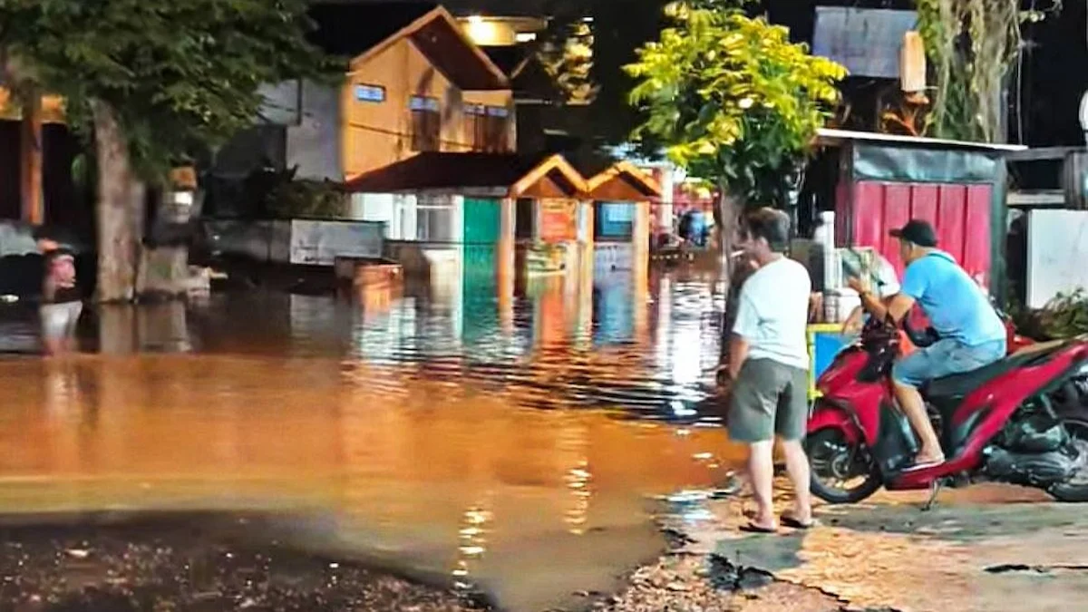 Genangan banjir merendam jalan permukiman saat hujan deras di Manado malam hari