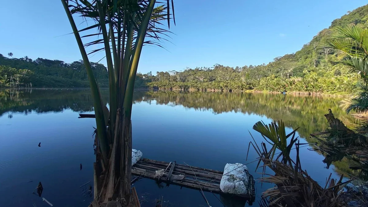 pemandangan Danau Kapeta Sitaro dengan air tenang dan hutan hijau