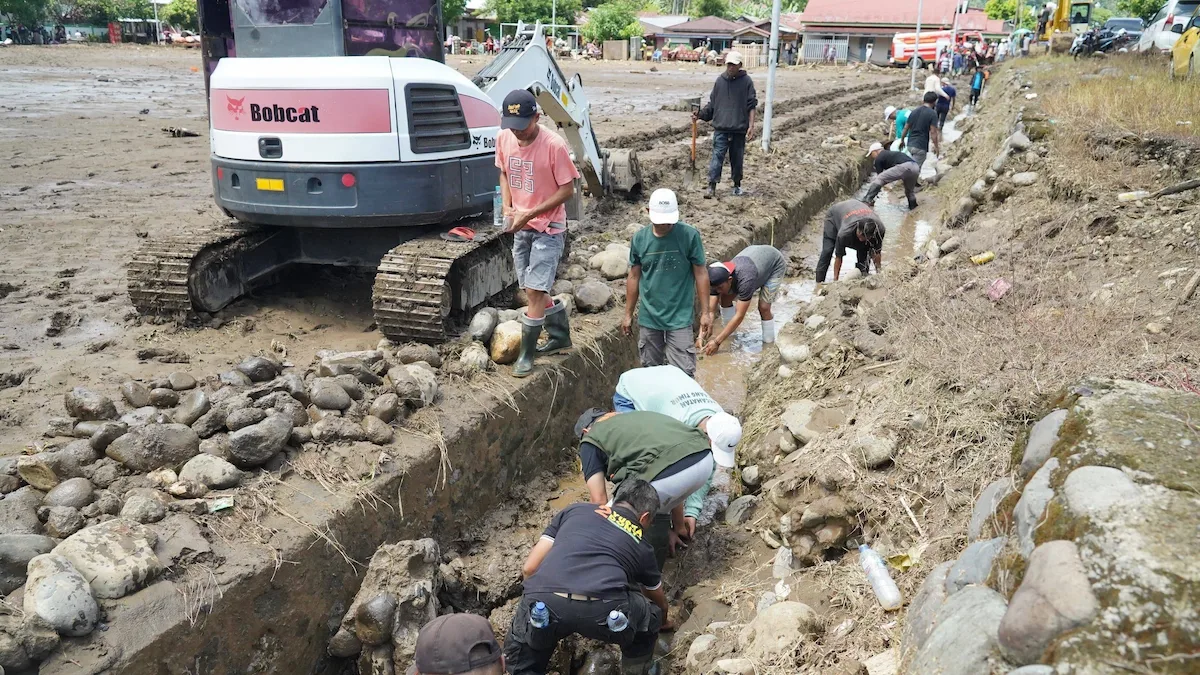 Petugas dan warga membersihkan saluran pascabanjir bandang di Bolmong menggunakan alat berat