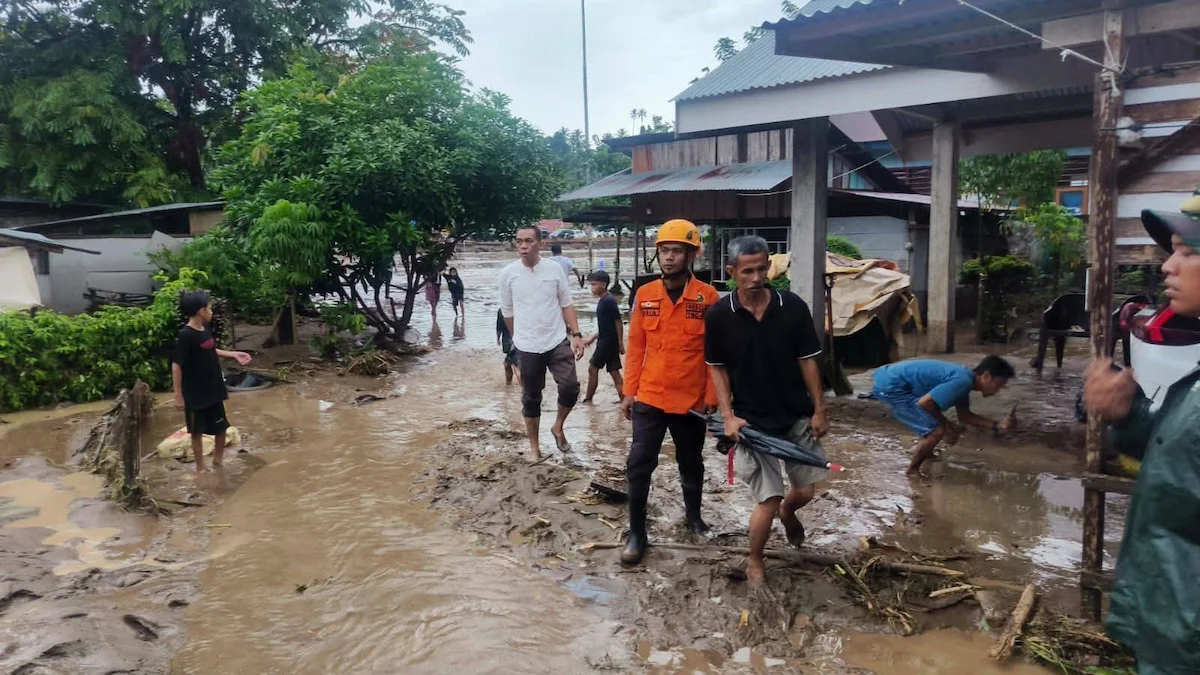 Warga dan petugas BPBD melintasi permukiman terdampak banjir bandang Bolmong