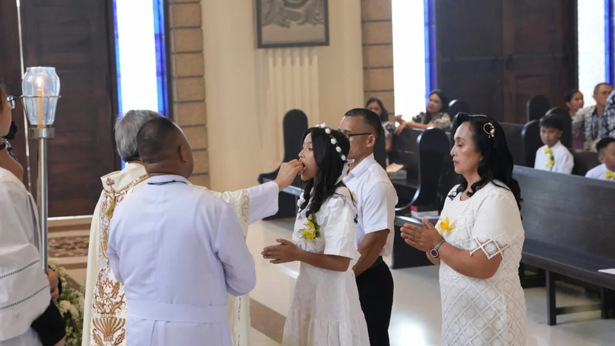 Seorang anak menerima Hosti Kudus saat Komuni Pertama di Paroki St Ignatius Manado